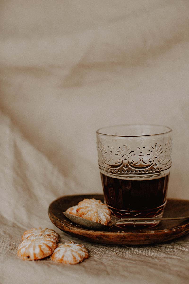 Ein schönes Glas mit Kaffe auf einer Untertasse mit einem Keks